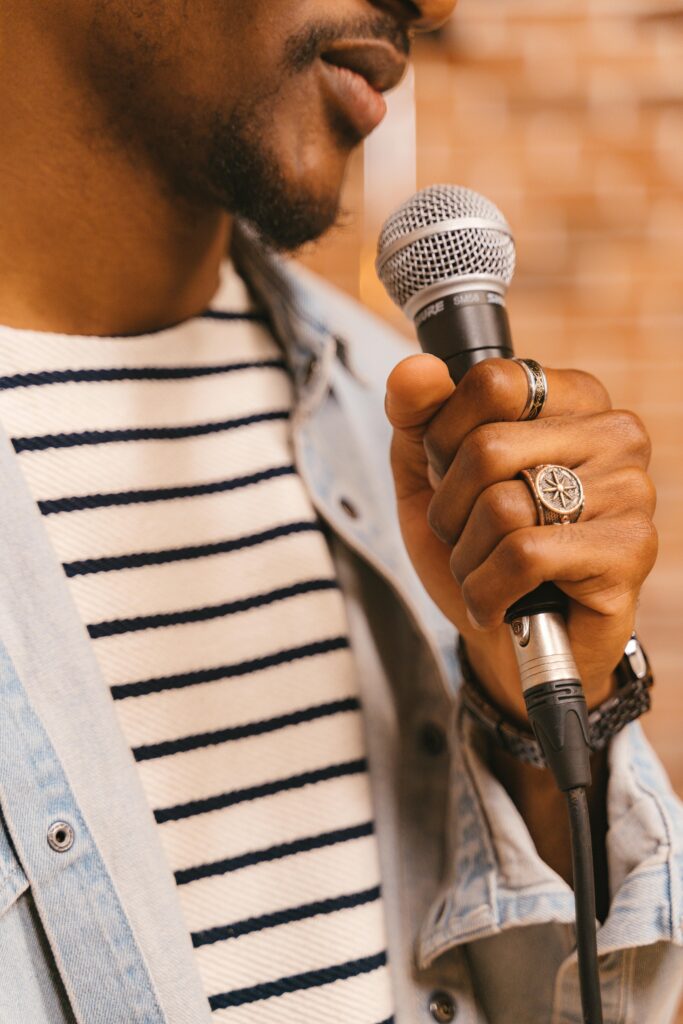 A man in a striped shirt holding a microphone, captured in a close-up shot.